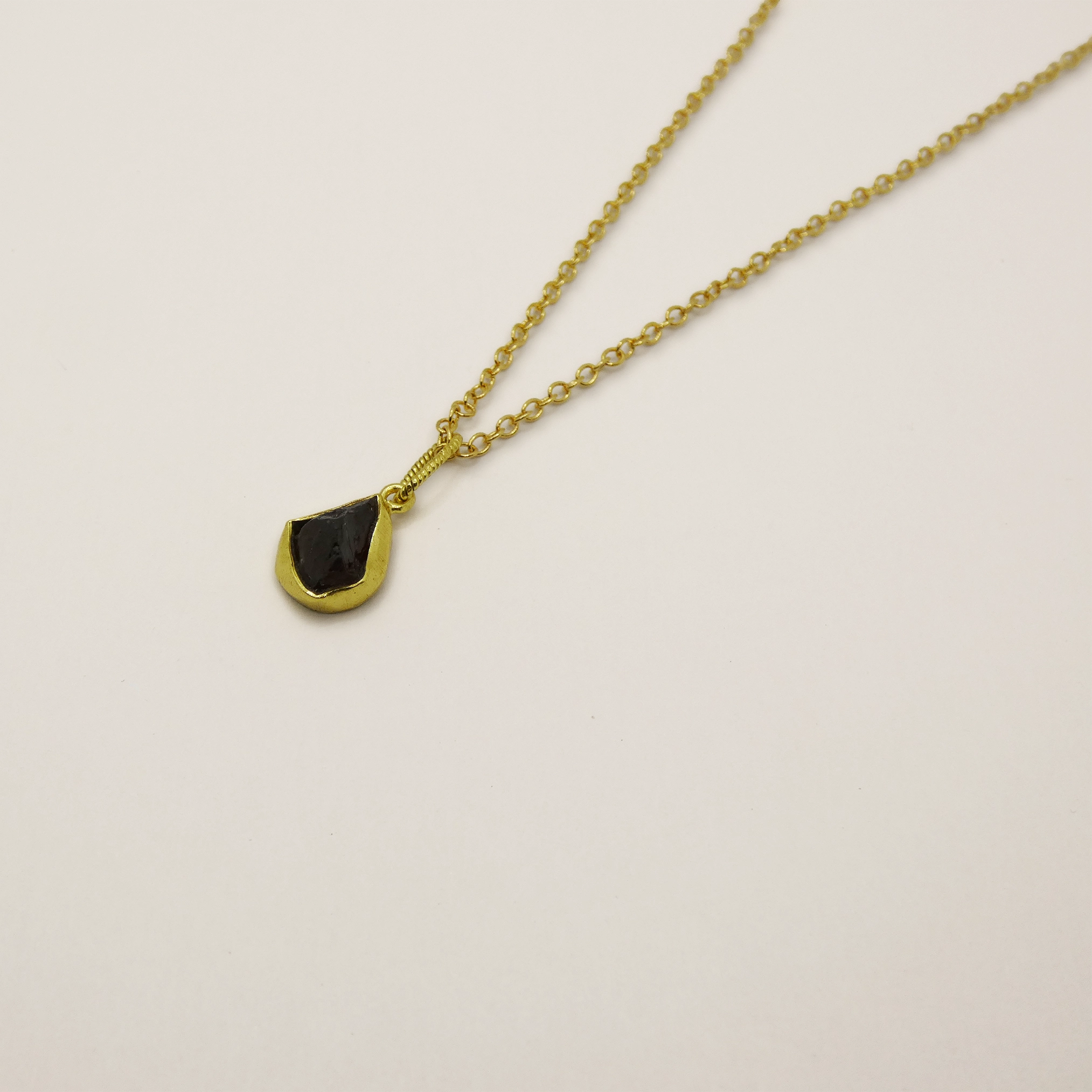 Pendentif Muja Juma plaqué or et grenat brut.